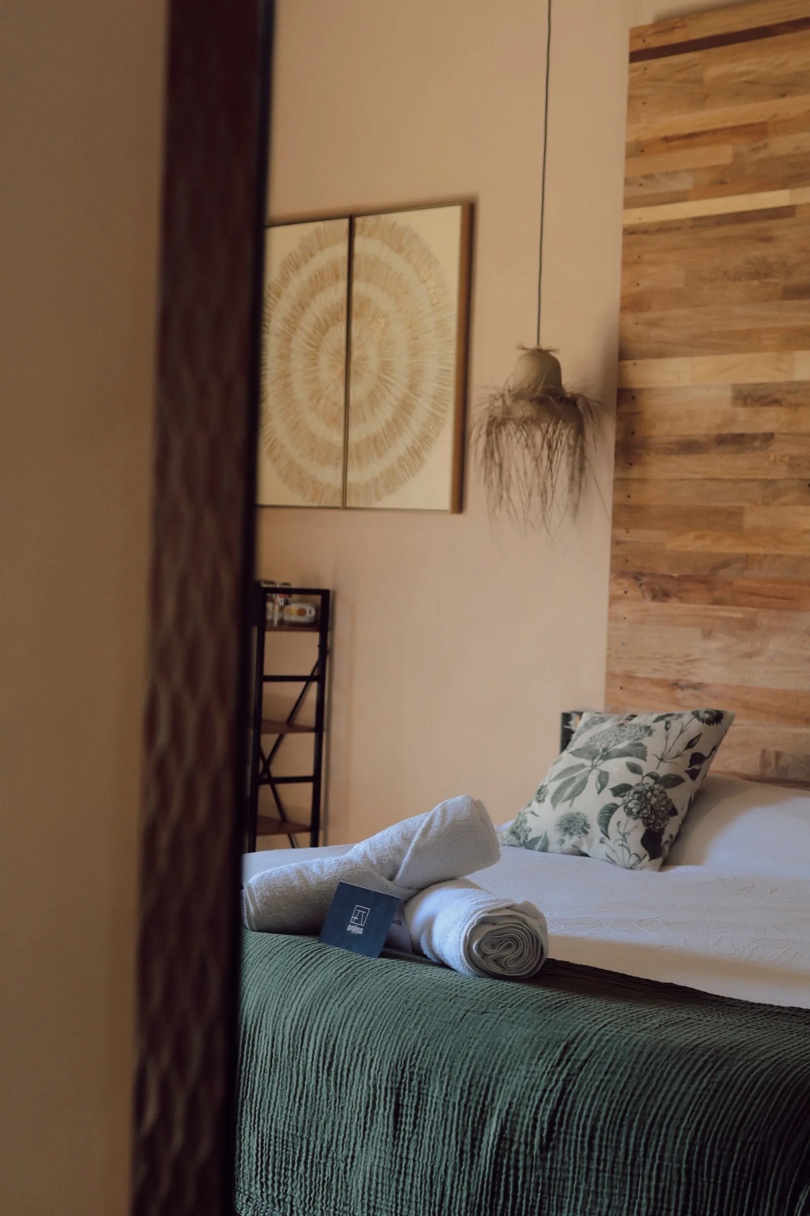 Cama tendida vista desde espejo con lámpara de mimbre